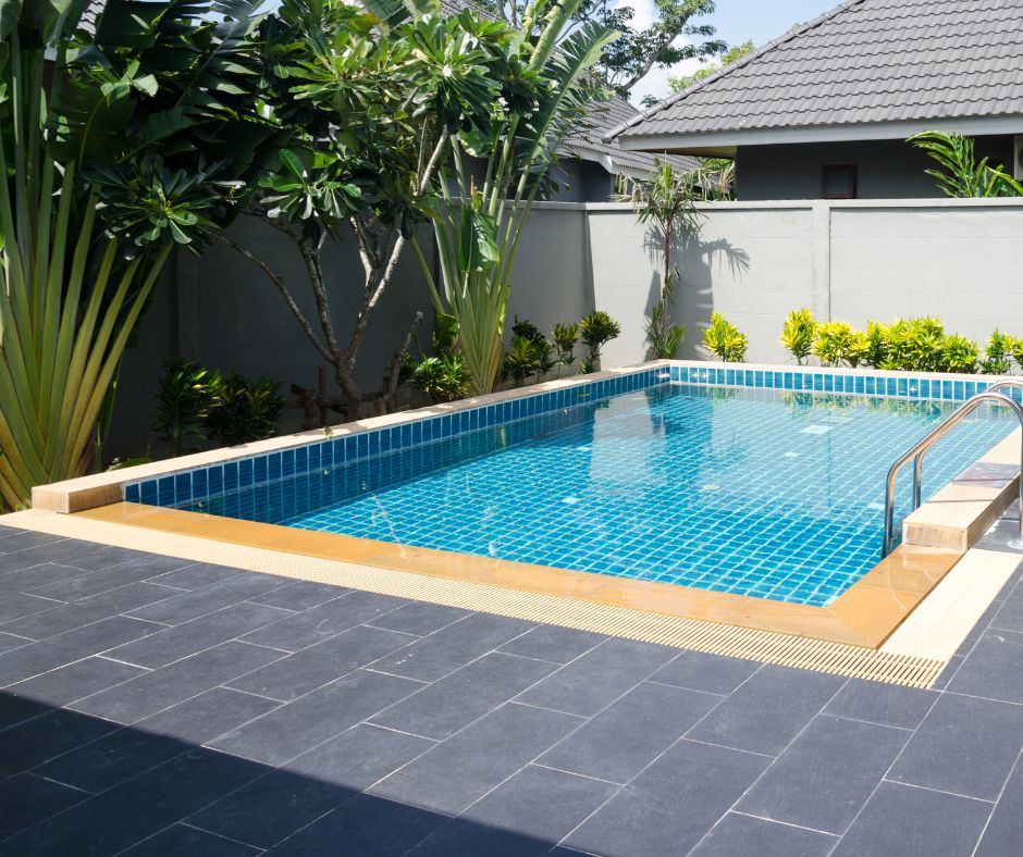Landscaped backyard pool area with paving and garden beds over the drainage pipes