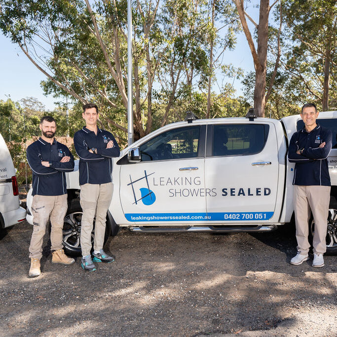Three members of the Leaking Showers Sealed team standing beside their branded work vehicle